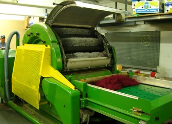 Wollverarbeitung mit der Kardiermaschine: Beim Kardieren werden die losen Wollfasern zu einem Vlies ausgerichtet. Dabei wird ein maisbasierter Kunststoff beigemischt, der den Stoff reißfest macht. Heraus kommt ein Vliesstoff, der am Ende als Isolation in die Jacke oder die Bettdecke kommt.