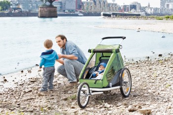 Vater steht mit Kinder und Fahrradanhänger am See.