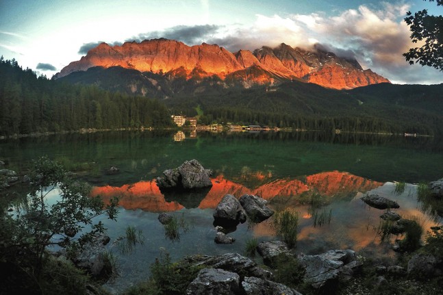 Der Eibsee (973 Meter) bei Grainau gilt aufgrund seiner Lage unterhalb der Zugspitze und des klaren, gr&uuml;n get&ouml;nten Wasser als einer der sch&ouml;nsten Seen der Bayrischen Alpen. Zum Sonnenuntergang spiegelt sich das dunkelrot leuchtende Zugspitzmassiv im See. | Foto: Christian Greither Photography