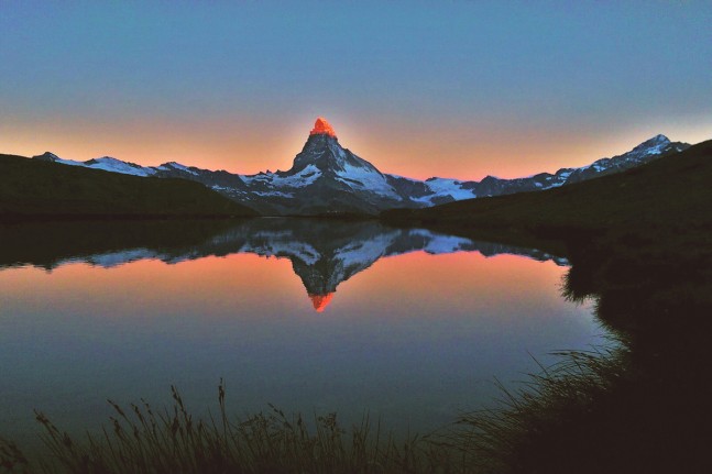 Einzigartig sch&ouml;n ist der Sonnenaufgang am Stellisee (2.537 Meter), wenn sich der bekannteste Berg der Schweizer Alpen - das Matterhorn - mit seiner rot leuchtenden Spitze im Wasser des Bergsees spiegelt. | Foto: Christian Greither Photography