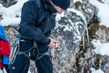 Eine Person trägt einen Klettergurt mit Eisschrauben.