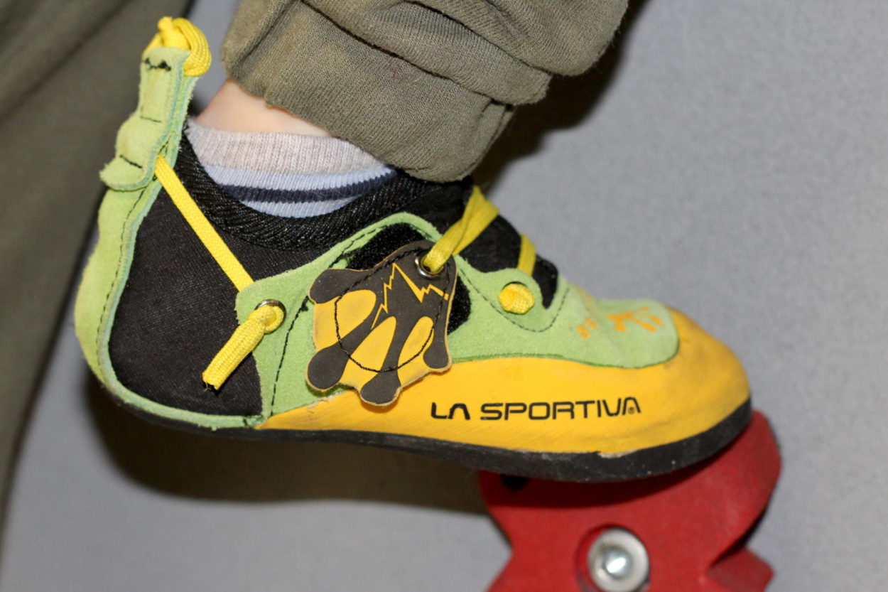 ein Kinderfuß mit Kletterschuh an der Kletterhallenwand