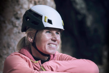Eine l&auml;chelnde Frau mit dem Mammut Wall Rider MIPS Kletterhelm auf dem Kopf.