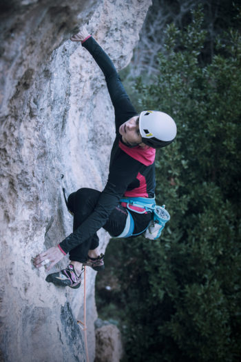 Eine Kletterin mit Helm an der Wand.
