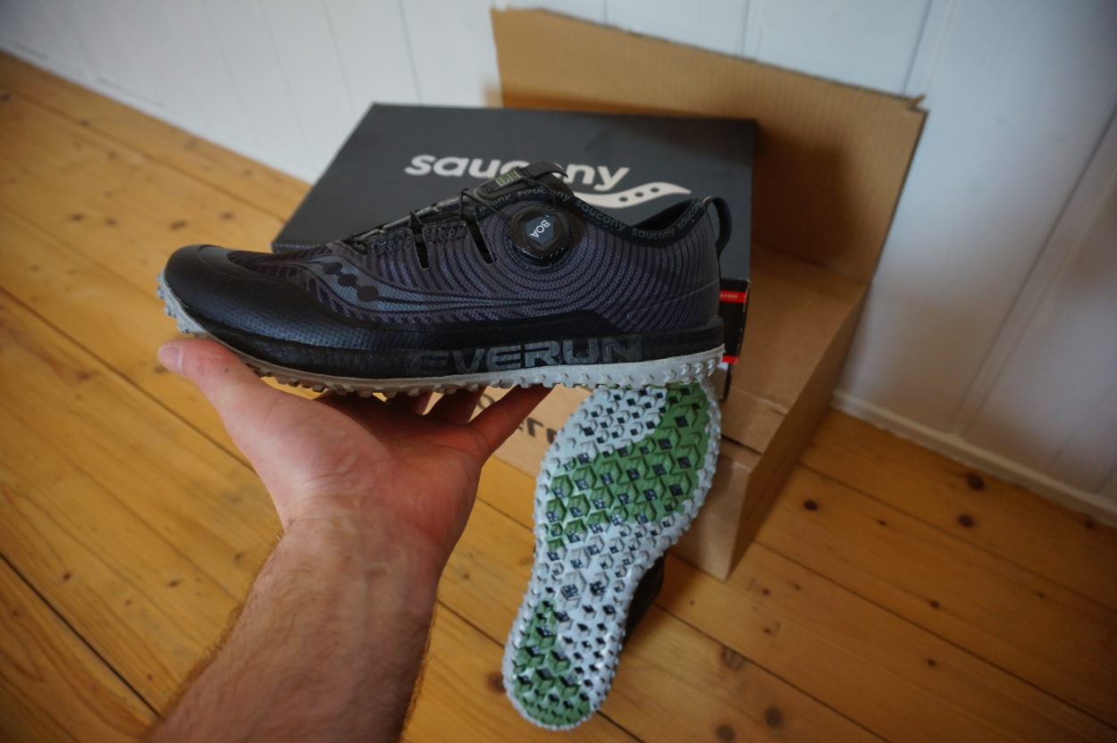 Mann packt Trailrunningschuh Saucony Switchback aus