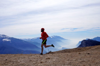 Trailrunner l&auml;uft vor Bergpanorama und See