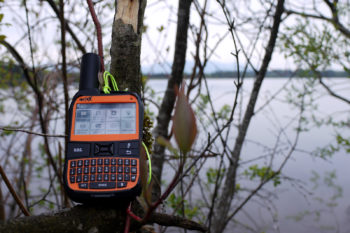 Der Spot X Satelliten-Messenger auf einem Ast vor einem See.