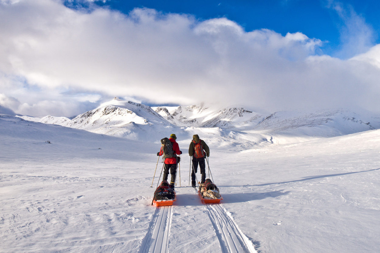 Zwei Ski-Wanderer mit Gepäckschlitten im Schnee.