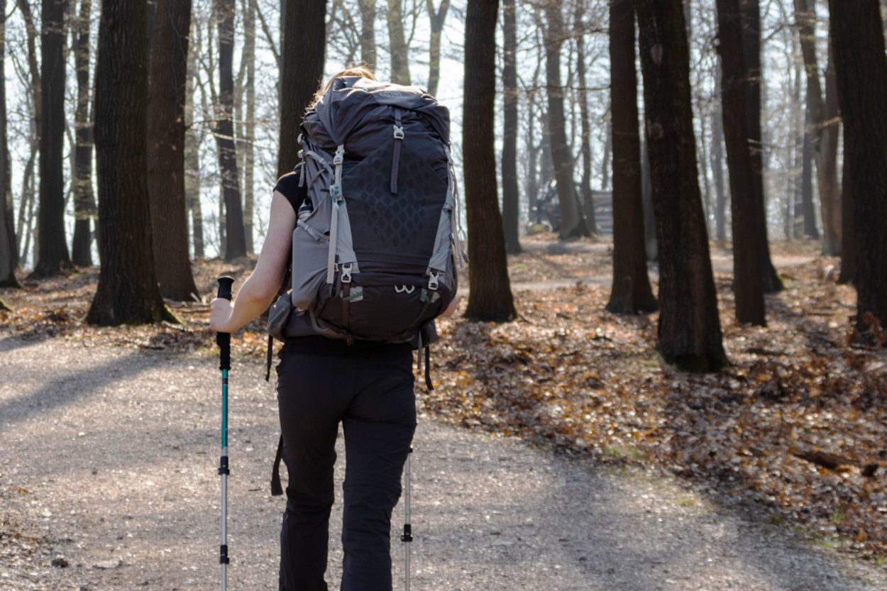 Wanderin auf Forstweg in Wald von hinten