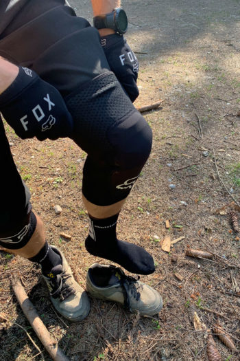 Mountainbiker zieht im Stehen seine Knieprotektoren an