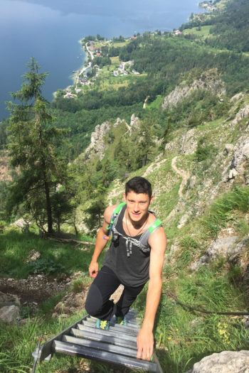 Ein Mann auf einer Leiter im Klettersteig, von oben fotografiert.