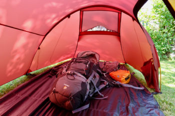 Im Inneren der Apsis liegt ein Rucksack auf dem Zeltboden, im Hintergrund die Bel&uuml;ftungs&ouml;ffnung, rechts die T&uuml;r.