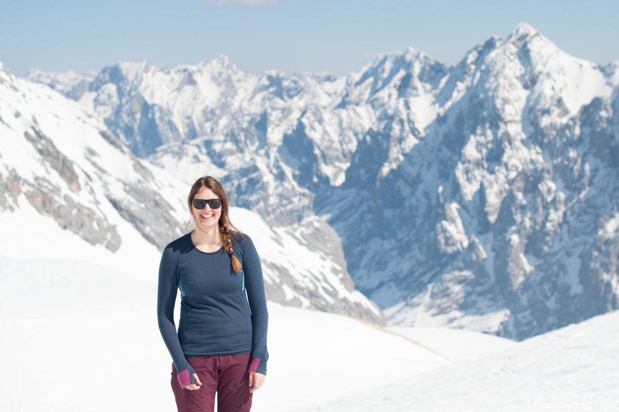 Frau steht in Merinoshirt Tuvegga Air Longsleeve von Devold im Frühjahr vor Bergpanorma