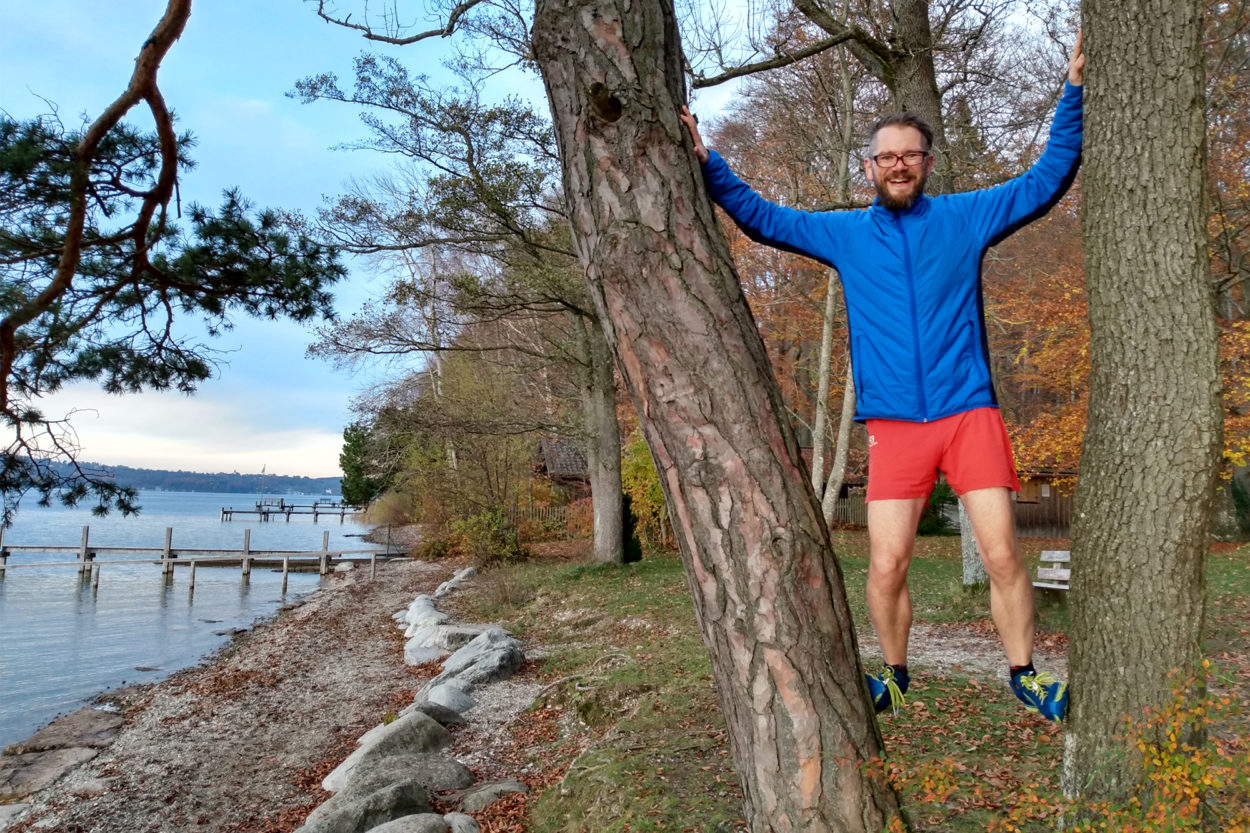 Trailrunner steht zwischen Bäumen am Starnberger See