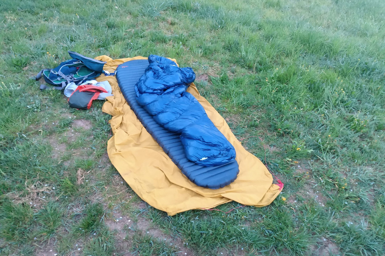 Aufgeblasene Isomatte mit Schlafsack im Gras