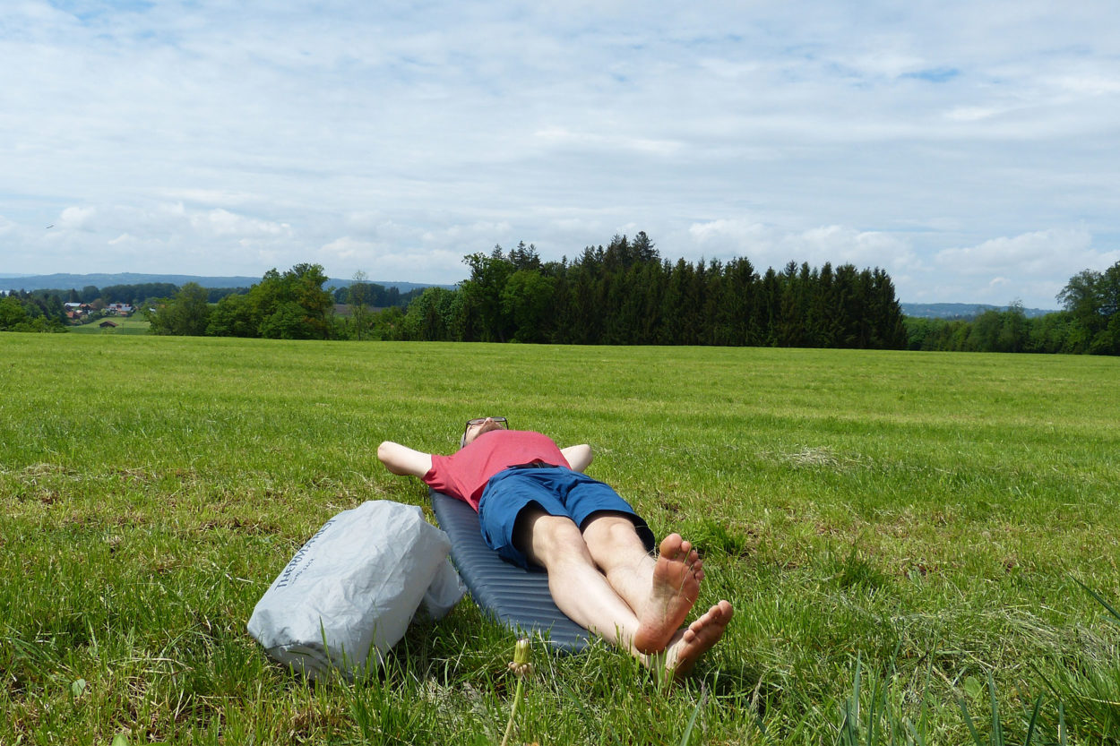 Mann auf Isomatte im Gras
